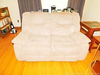 Front view of beige fabric recliner couch showing two seats and padded armrests.