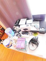 View of all electronic items on table including players, router box, headphones, power strip, remotes, CDs, cables.