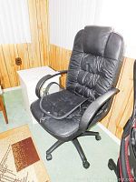 Full view of black office chair showing padded faux leather upholstery, armrests, and wheel base.