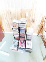 View of multiple stacks of DVDs in standard cases arranged on floor and in CD towers.