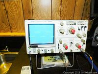 Front view of Kikusui COS5041 oscilloscope showing screen with waveform and control panel with knobs and input connectors.