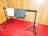 Full view of adjustable backdrop stand holding black and white fabric backdrops over red floor and wood paneled wall background.