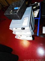 View of stacked plastic bins including the black tray with assorted computer electronics repair items on top.