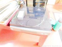 Sony turntable with transparent dust cover on a wooden surface, showing the full unit lengthwise.