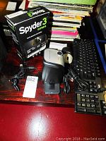 Photo showing Datacolor Spyder 3 Express color calibration device with box, connected USB cable, Dell wired mouse, and black wired keyboard arranged on a table.