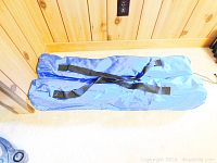 Two blue nylon carry bags for foldable chairs laid on floor.