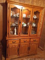 Front view of wooden china cabinet with glass doors and interior light on
