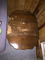 Top view of the wooden end table showing the carved detail and worn finish.