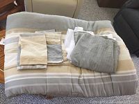 Comforter set components laid out folded on a chair, showing stripes in grey, tan, and cream colors.