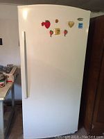Front view of the large white upright freezer with decorative magnets on the door.