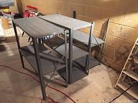 Three metal shelving units in a basement setting against a concrete block wall with some storage items nearby. Units are gray metal with perforated side frames.