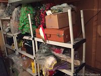 Shelves with assorted boxes, plastic wrapped items, and holiday decor items including wreaths and ribbons.