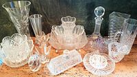Full view of all 17 cut glass and crystal pieces including decanter, vases, bowls, butter tray, and glasses arranged on a wooden table.