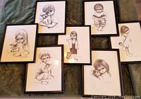 Full set of seven framed vintage pencil drawings of children with big eyes by Ozz Franca laid out on blanket.