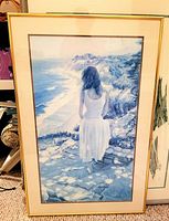 Full view of framed print featuring a woman overlooking a coastal scene.