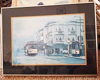 Framed print showing San Francisco street car on city street with buildings, matted and framed.