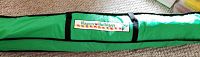 Closed green carry bag with 'Happy Holidays' label containing artificial Christmas tree.