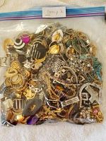 Plastic Ziploc bag marked 'Group 2' filled with assorted vintage jewelry pieces including chains, earrings and other decorative elements in gold and silver tones with black and white accents.