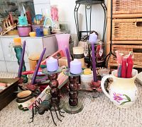 Collection of assorted candles and holders with focus on purple candles and ant-shaped holder