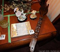 Two Lily Collection ceramic figurines, 6 flamingo glass stirrers in original packaging, and large carved African wooden spoon and fork set on wooden table.
