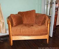 Front view of the brown polyester bucket chair showing the wooden frame, tufted seat cushion, and three matching cushions.