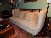 High back beige herringbone sofa with 7 matching pillows arranged on it, placed in a living room setting.