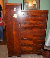 Front view of tall boy dresser showing six drawers and side armoire door, wood grain finish visible, metal handles on drawers and door, wear and nicks visible on surface.