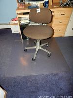 Desk chair and carpet protector mat on floor showing chair from front angle