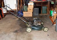 Photo of Bolens lawnmower from a side angle showing the full body, wheels, handle, and engine in a garage setting.