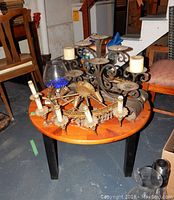 Photo of wood coffee table with antique electric wall sconce and antique metal five candle candelabra on top in a storage area.