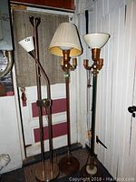 Photo showing all three lamps together: a torch-style lamp, a traditional lamp with pleated lampshade, and a bowl shade floor lamp