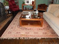 Full view of the rectangular area rug with border patterns and fringed edges, placed under a wooden coffee table in living room setting.
