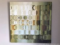Photograph of a square abstract wall art painting with a pattern of circles and rectangles in colors including deep green, grey, bronze, and beige tones.
