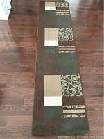 Full length view of the carpet runner laid flat on wooden floor showing overall pattern and colors
