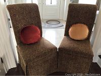 Front view of two upholstered dining chairs with round decorative pillows on seats