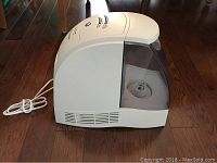 Side view of white Honeywell humidifier showing translucent water tank and air vents on wooden floor.