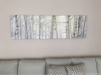 Frontal view of entire canvas print showing birch trees in snow above sofa.