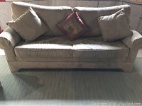 Front view of beige microfiber sofa showing two large matching cushions and one decorative pillow in the center.