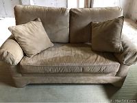 Light brown plush microfiber love seat sofa with two matching pillows, cushioned arms, and wooden base.