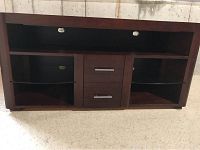Front view of solid wood TV stand showing the open top shelf, two side compartments with glass shelves, and two central pull-out drawers with metal handles.