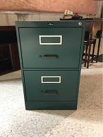 Front view of the green metal filing cabinet showing two drawers with label holders and handles.