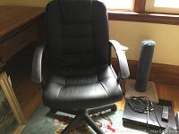 Front view of the black leatherette office chair showing padded seat, back, armrests, and base.