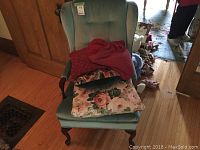 Front view of light blue wingback chair with cushions piled on seat