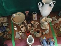 Overview of all items within green tape: porcelain urn, bowl, pitchers, vases and trinket boxes