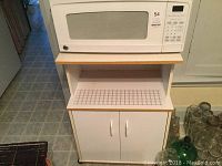 General Electric microwave placed on top of a white cabinet with grid-patterned countertop