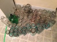 Wide view of the collection of aqua and clear glass jars and bottles arranged on the floor