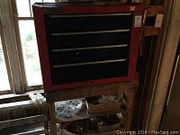 Red Mastercraft four drawer tool chest on wooden workbench with some hardware containers under the bench.