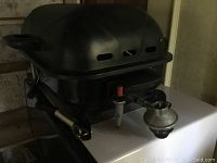Side view of the portable BBQ grill showing the propane adapter and control valve.