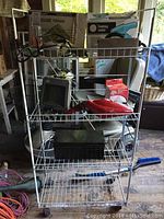 Full view of the white metal shelving unit showing multiple items stored on the shelves including tools and small appliances.