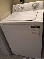Front view of white General Electric top loading washing machine with Energy Guide label visible on the front panel.